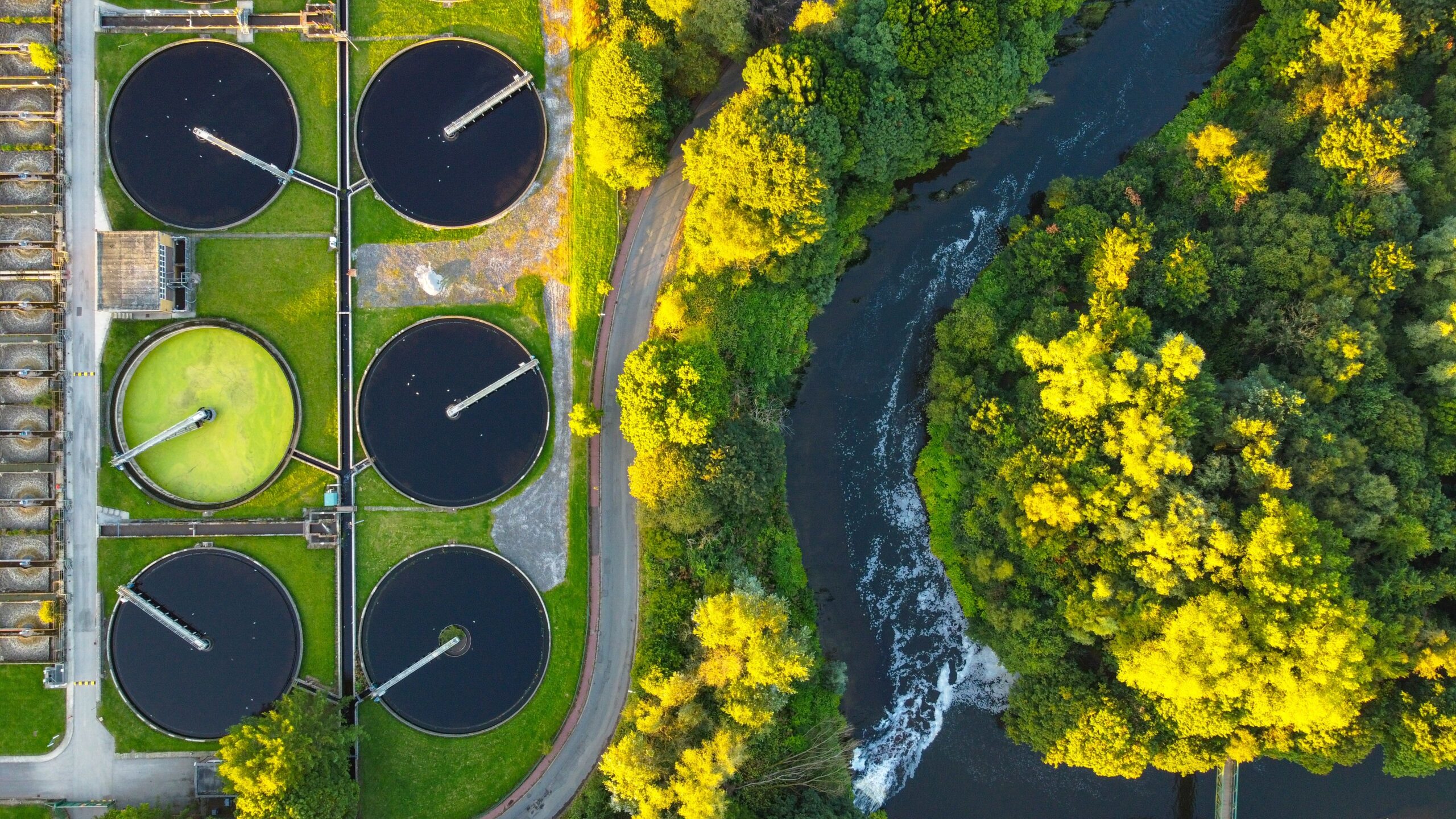 A water treatment plant with round tanks and trees.