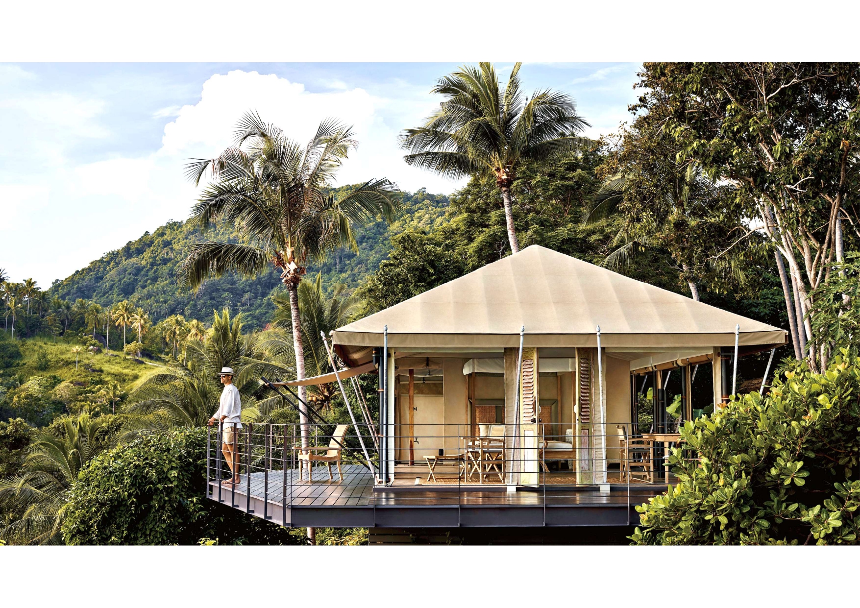 A man standing on a deck with a tent and chairs on it.