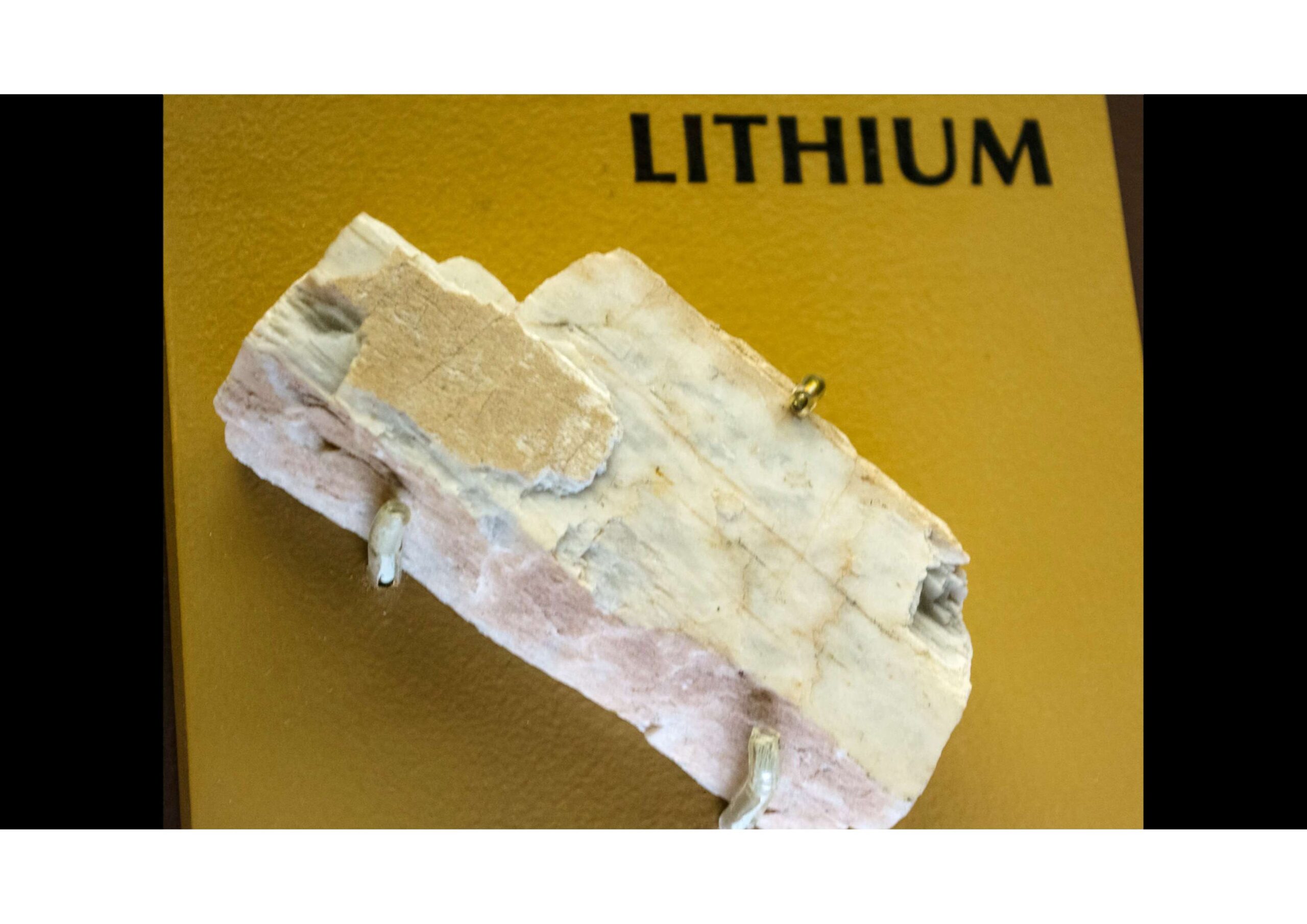 A lithium ore sample displayed on a yellow background with the word "LITHIUM" printed above it.