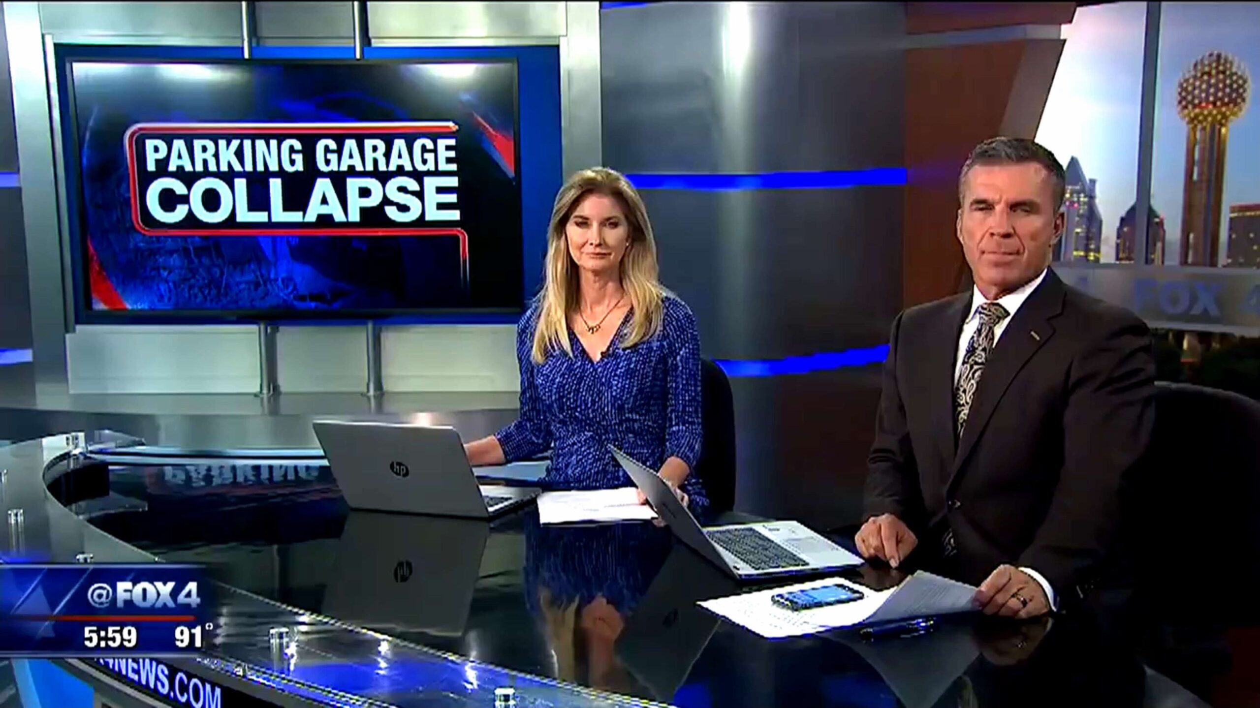 Two news anchors sit at a desk in a TV studio with a screen behind them displaying "Parking Garage Collapse." The broadcast is on FOX 4, and the time reads 5:59 with a temperature of 91°F.