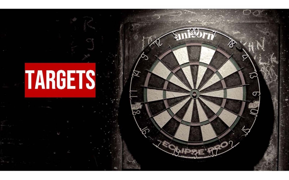 A dartboard on a dark wall with the word "TARGETS" in bold red and white text on the left side.
