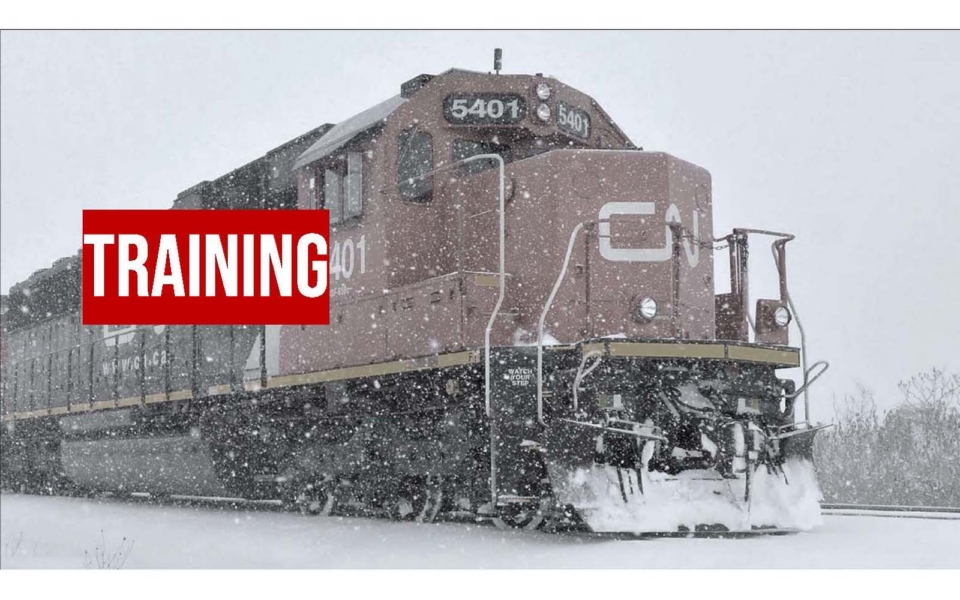 A red and black locomotive travels on snowy tracks during a snowstorm. A bold red box with the word "TRAINING" overlays the image.