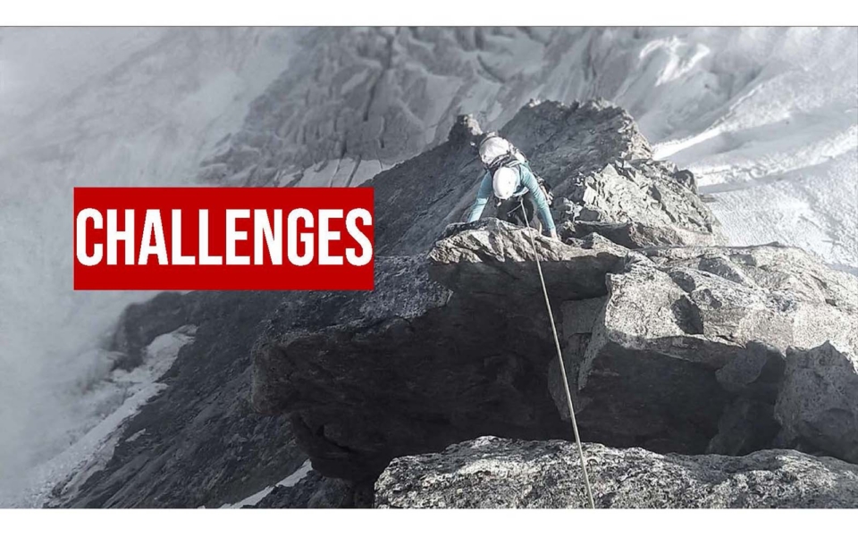 A climber ascends a steep, rocky mountain slope with a rope; the word “CHALLENGES” appears in bold red text on the left.